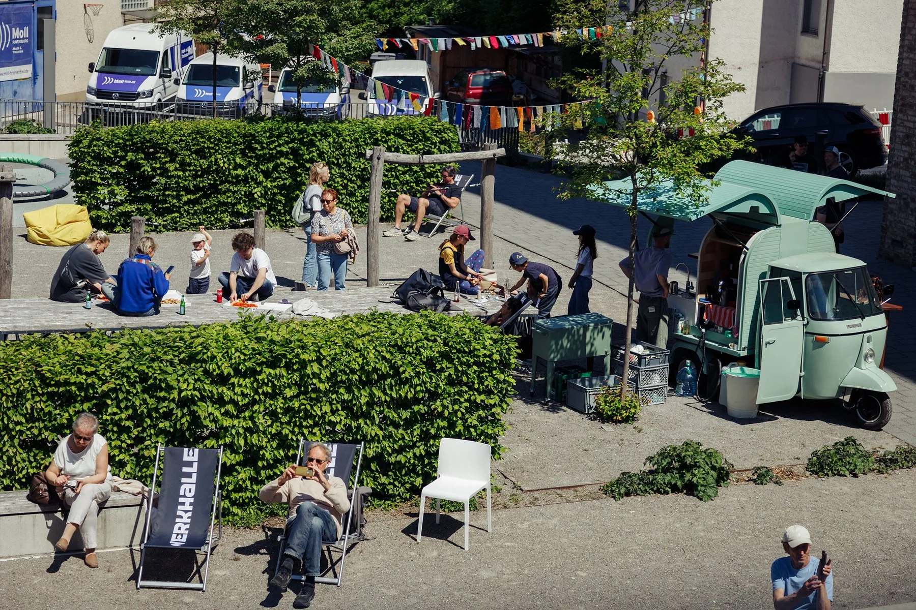 Vogelperspektive auf Stadtplatz mit Wimpeln, Menschen und Pocissimo Coffee Ape